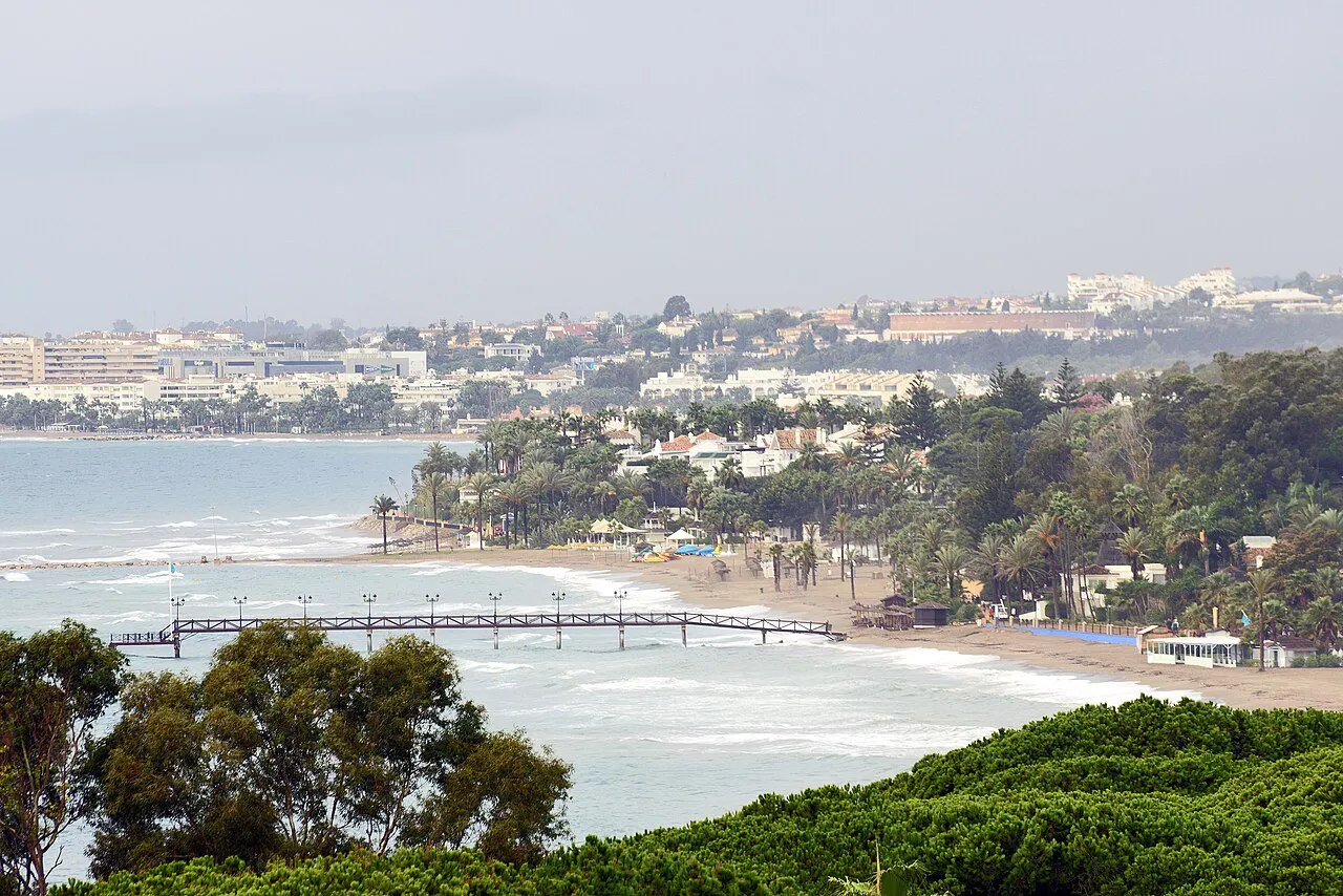 Wooded Golden Mile coastline west of Marbella centre with a long wooden pier reaching into the sea
