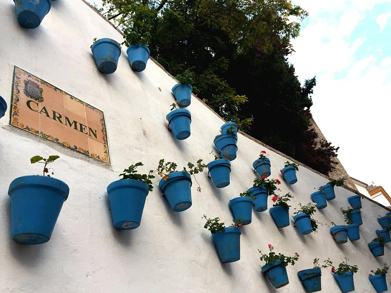 Whitewashed wall hung with blue flowerpots on Calle Carmen in Marbella's Old Town