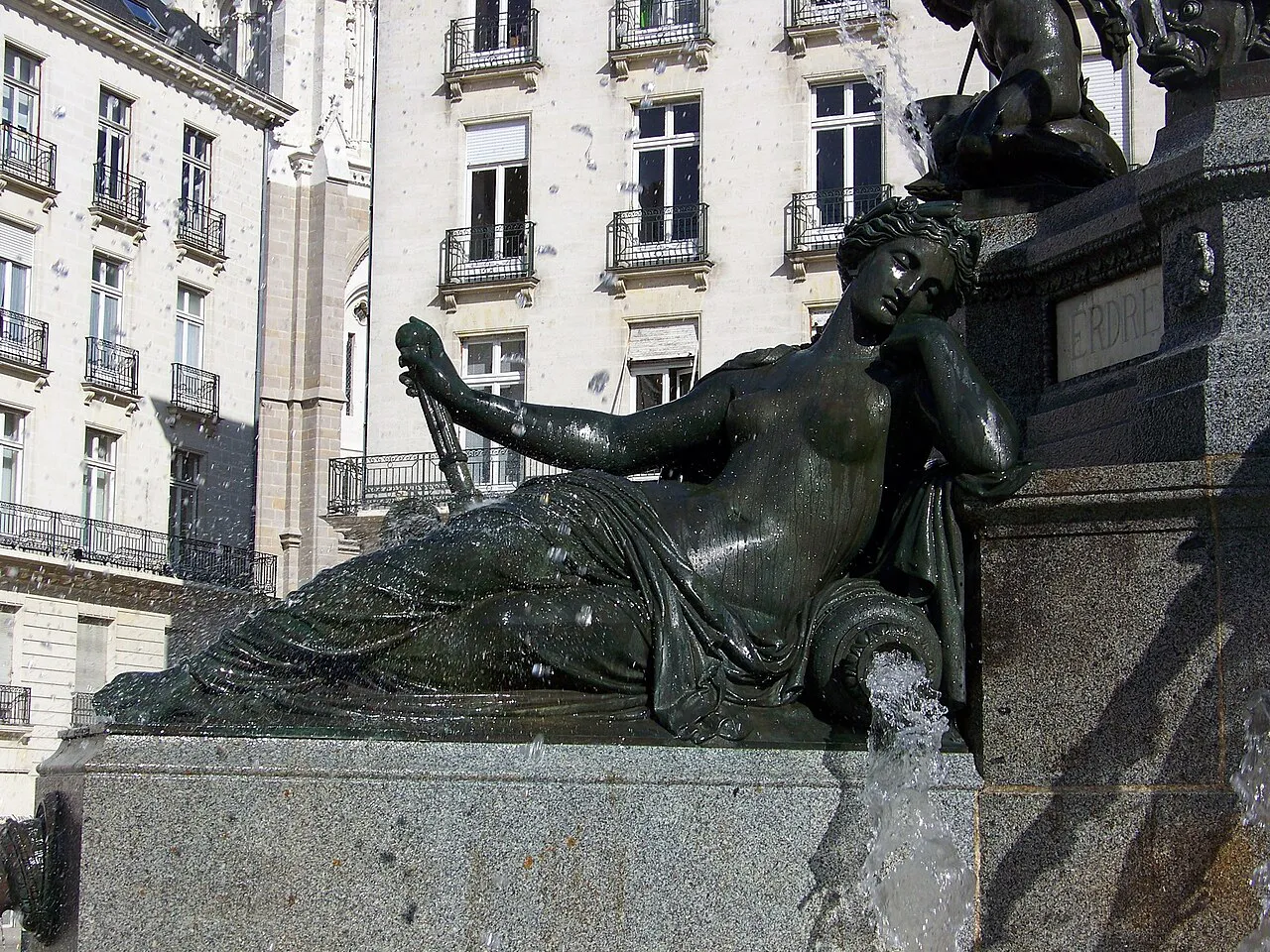 Bronze allegorical statue of the Erdre on the Place Royale fountain in Nantes, with stone apartment façades behind