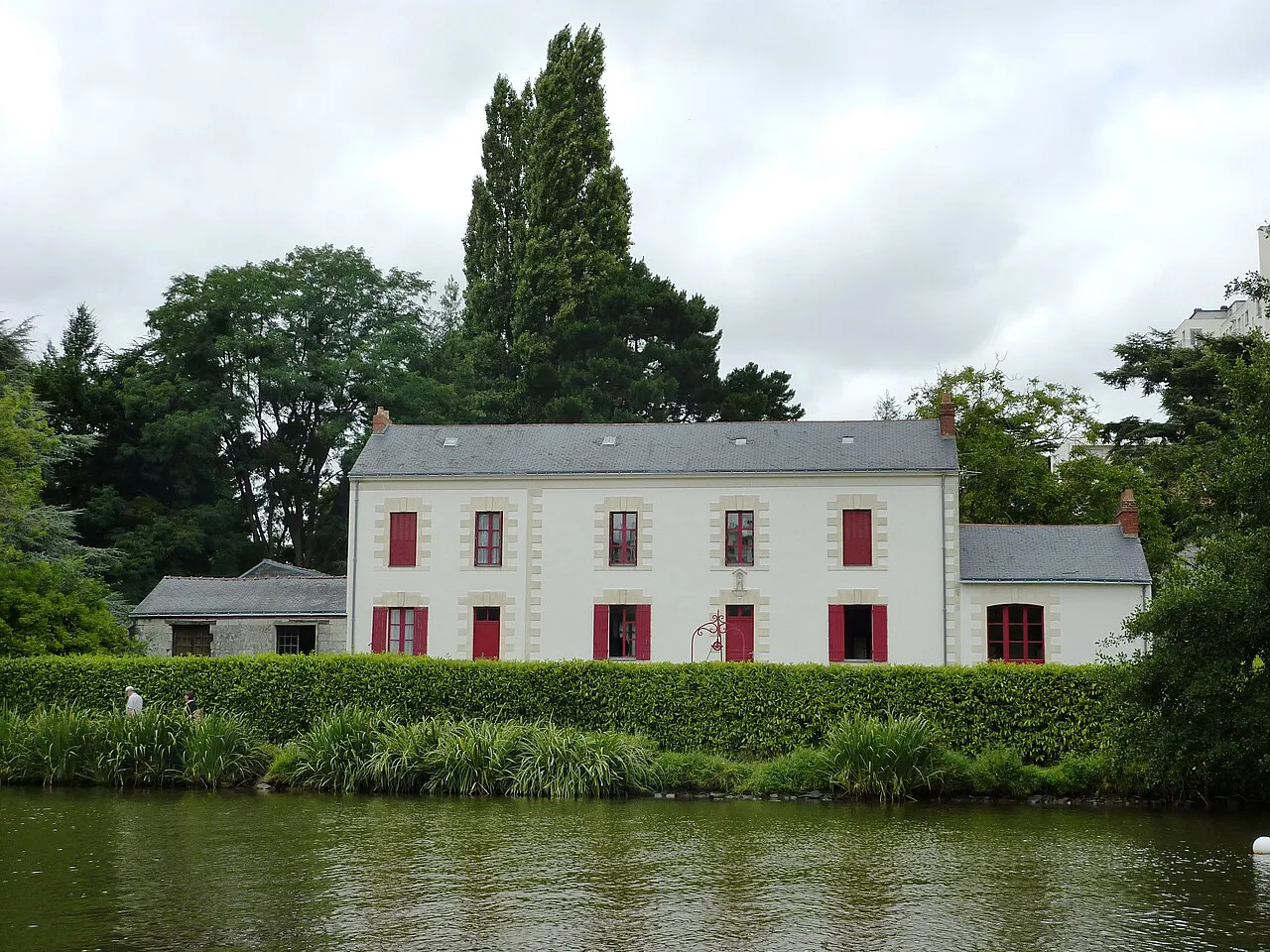 White house with red shutters on the green bank of the Erdre river in north Nantes