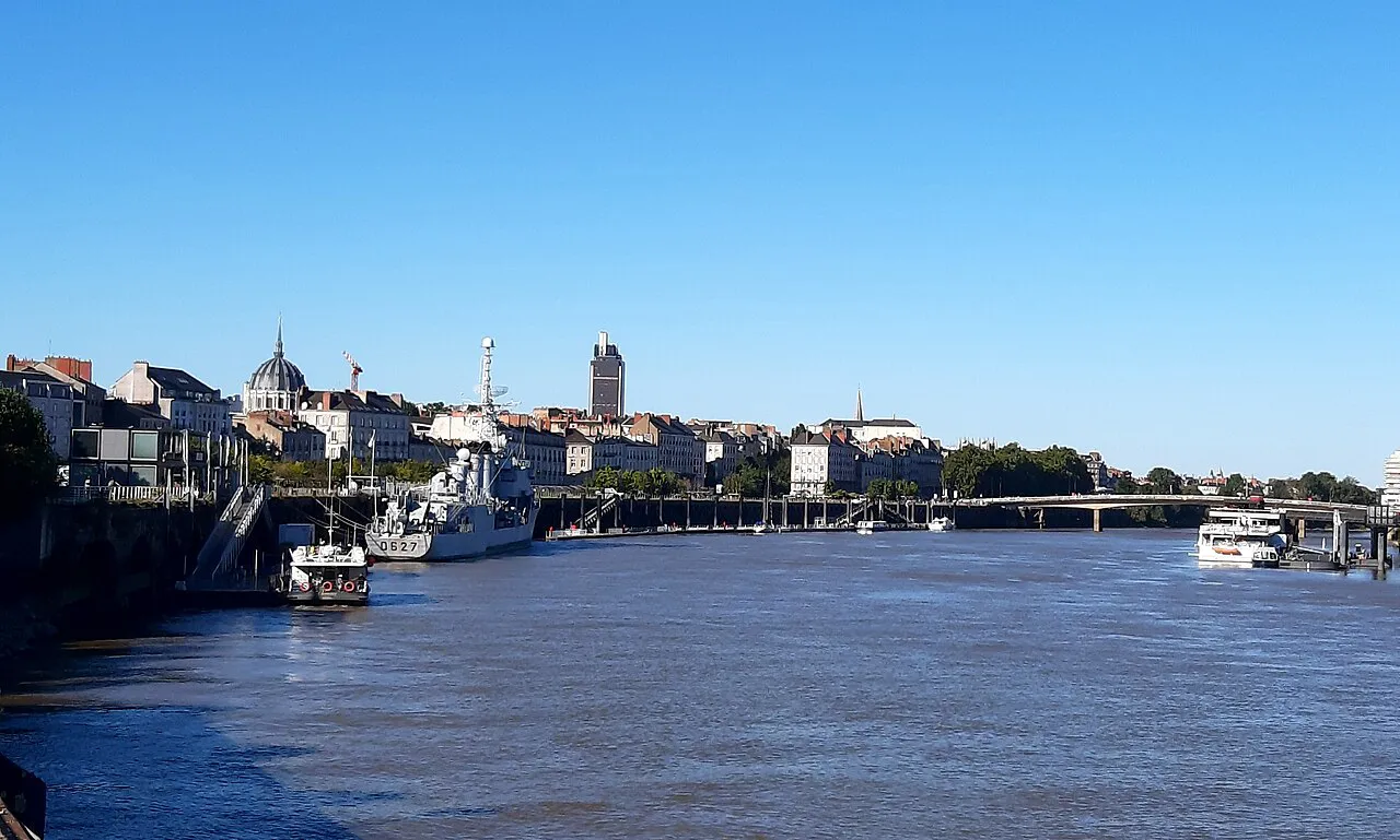 The Loire at Quai de la Fosse in Nantes, with moored boats and the city skyline under a clear blue sky