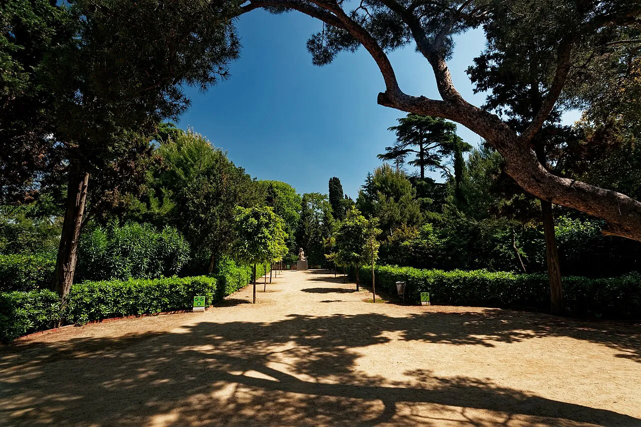 Shaded sandy garden path lined with hedges and pines in the Jardins de Laribal on Montjuïc, Barcelona