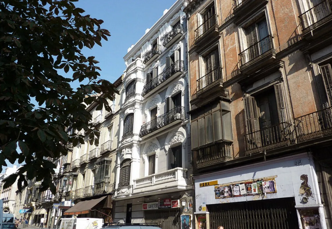 Ornate white and brick apartment façades with iron balconies along Calle de Atocha in central Madrid