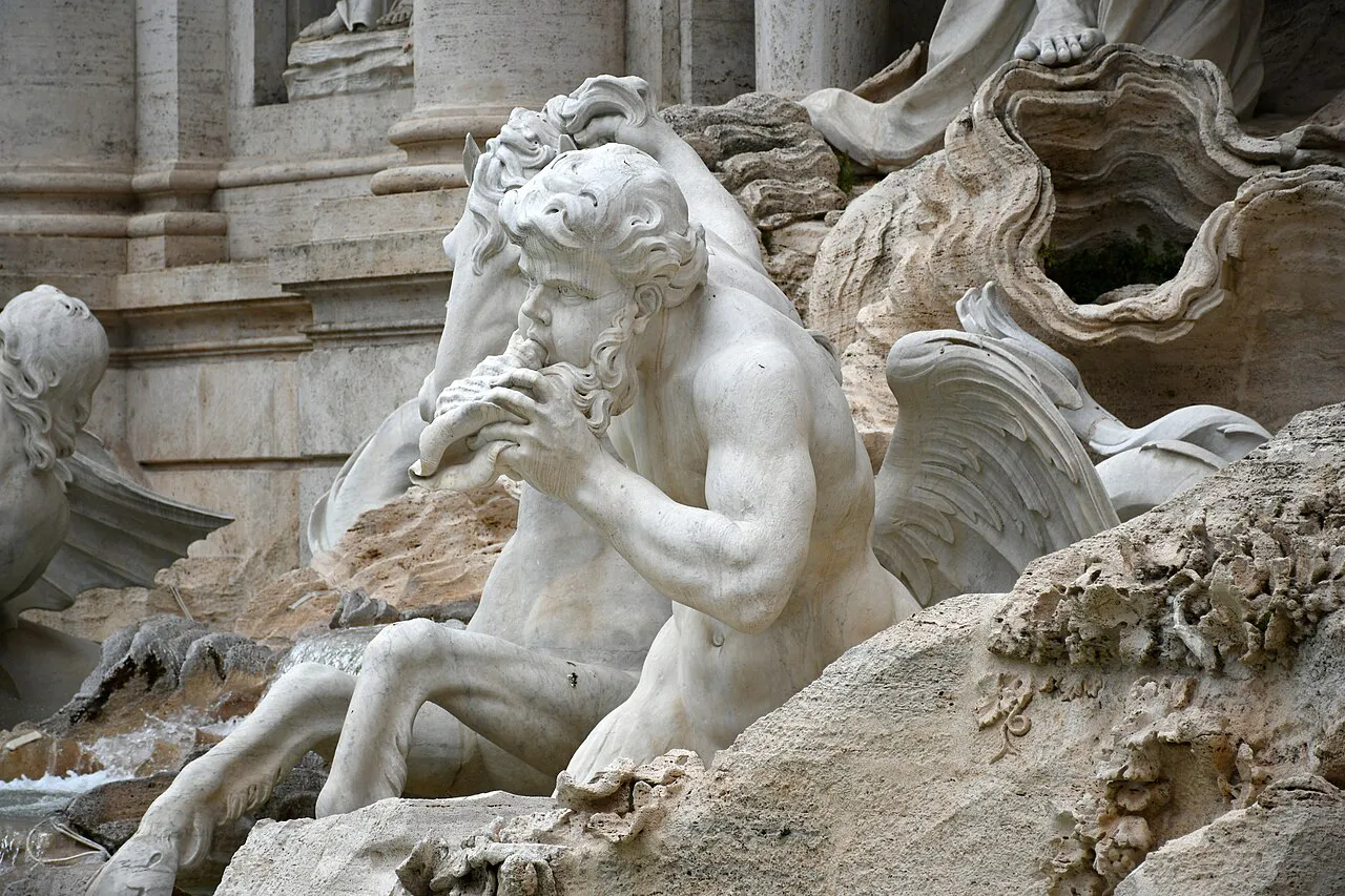 Close-up of a marble triton sculpture blowing a conch shell on the Trevi Fountain, Rome