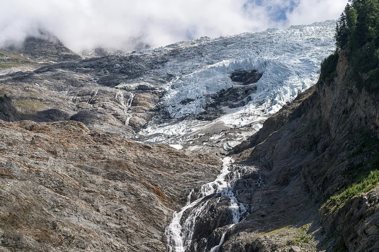 Crevassed ice of the Glacier des Bossons above a meltwater stream and bare rock, Chamonix valley