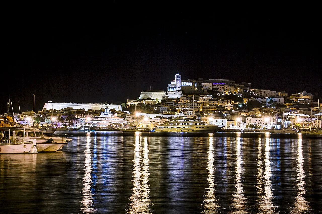 Dalt Vila and the Ibiza Town waterfront lit at night, reflected in the harbour