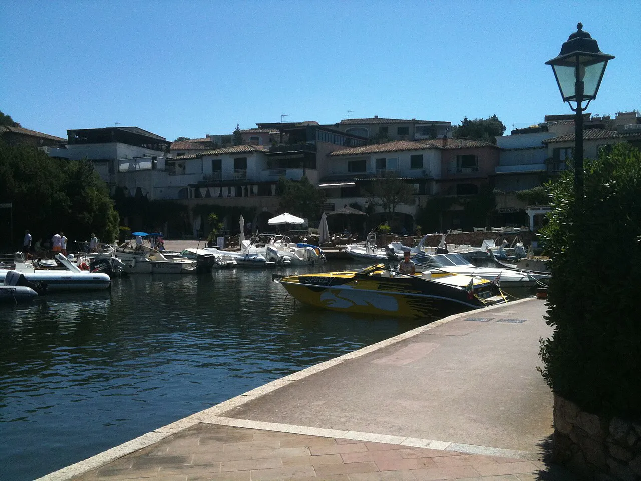 Motorboats moored along a waterside promenade in the Porto Cervo marina on a sunny day