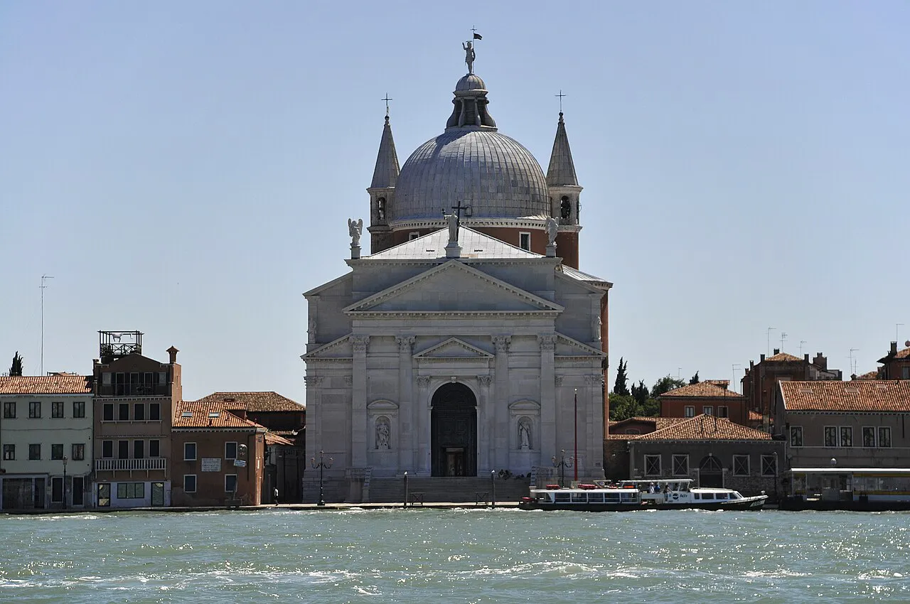 White facade and dome of Il Redentore church on the Giudecca waterfront, Venice, seen across the canal