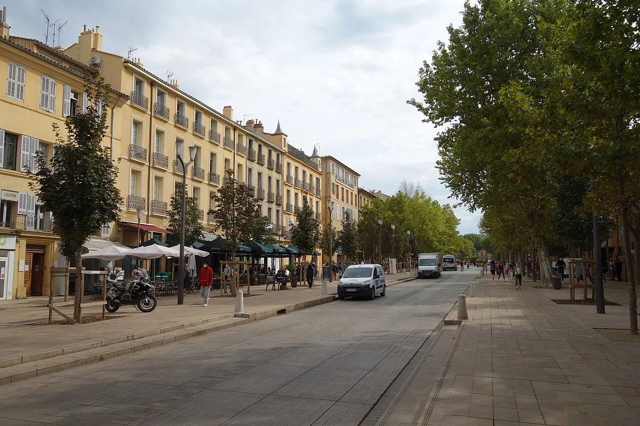 Tree-lined Cours Mirabeau with pale stone facades and café terraces in Aix-en-Provence