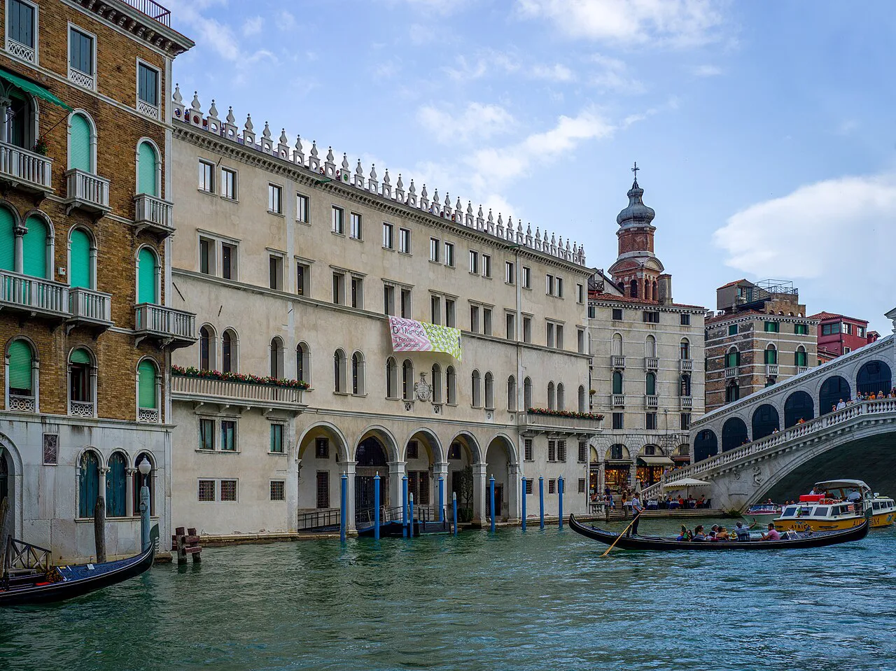 Fondaco dei Tedeschi and the Rialto Bridge on the Grand Canal in Venice, with a gondola passing