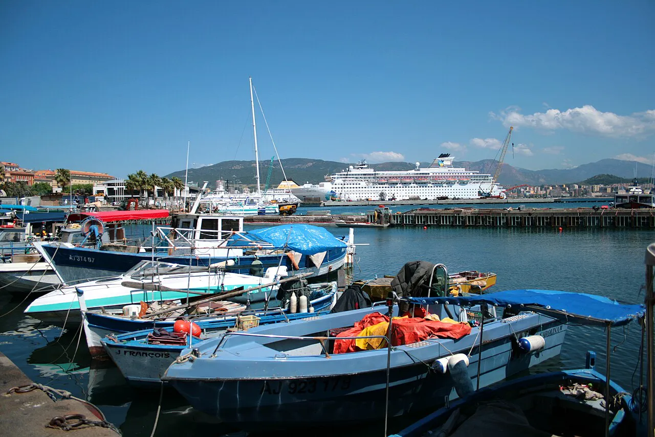 Small fishing boats moored in Ajaccio's Tino Rossi harbour beside the old town, with hills beyond