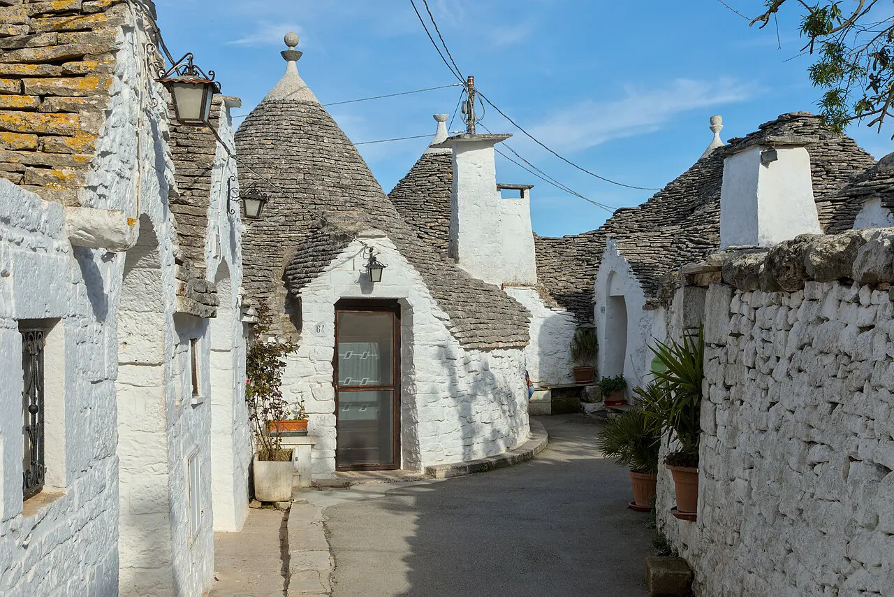 Quiet whitewashed lane lined with conical-roofed trulli in Alberobello's Rione Monti