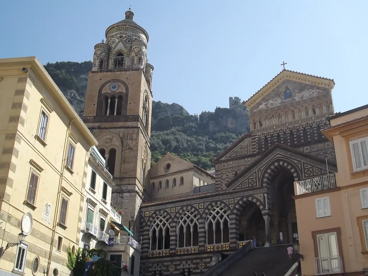 Striped facade and bell tower of Amalfi Cathedral rising above Piazza del Duomo