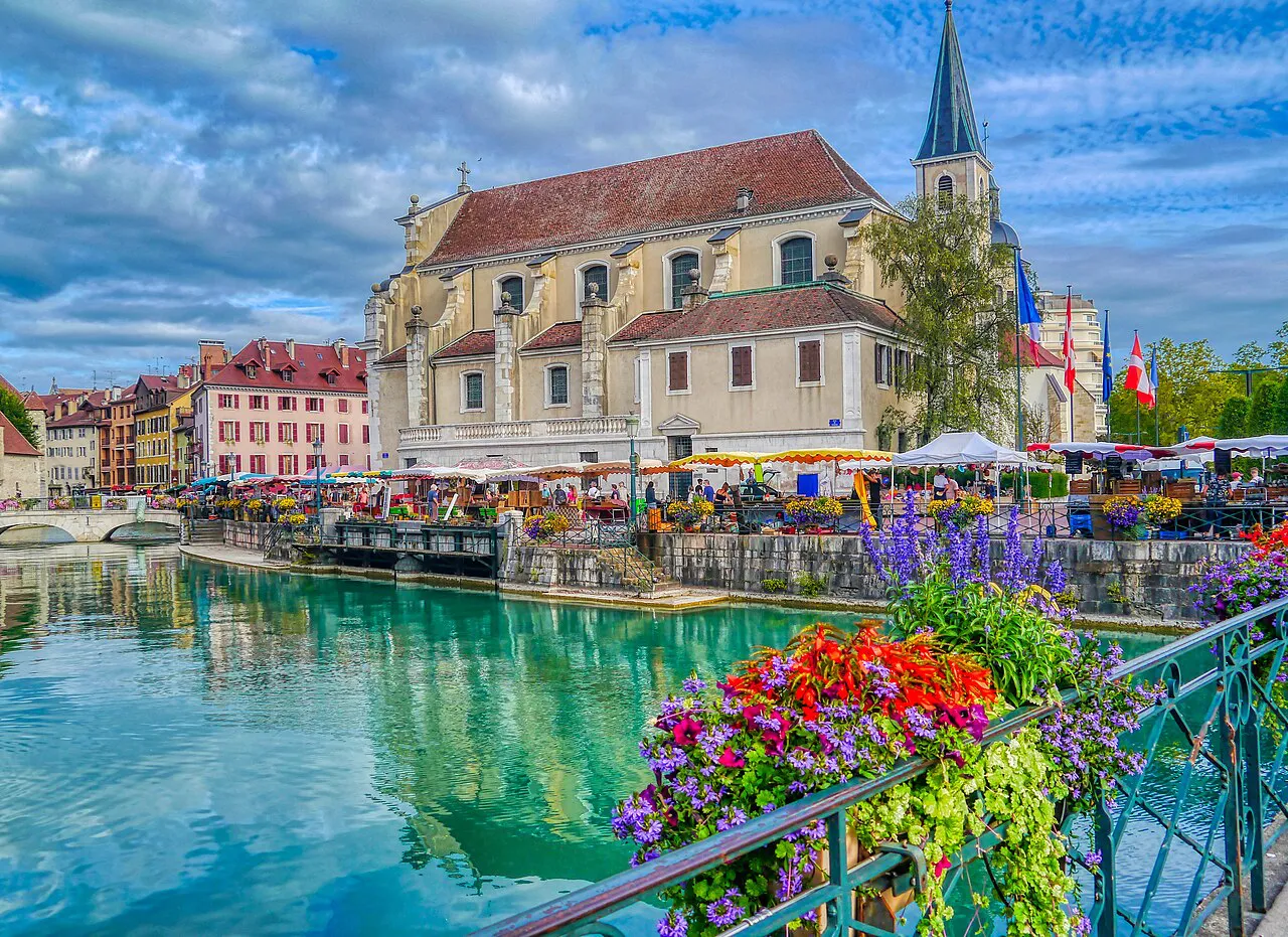 Church of Saint-François de Sales beside the turquoise Thiou in Annecy old town, with flower boxes on the railings