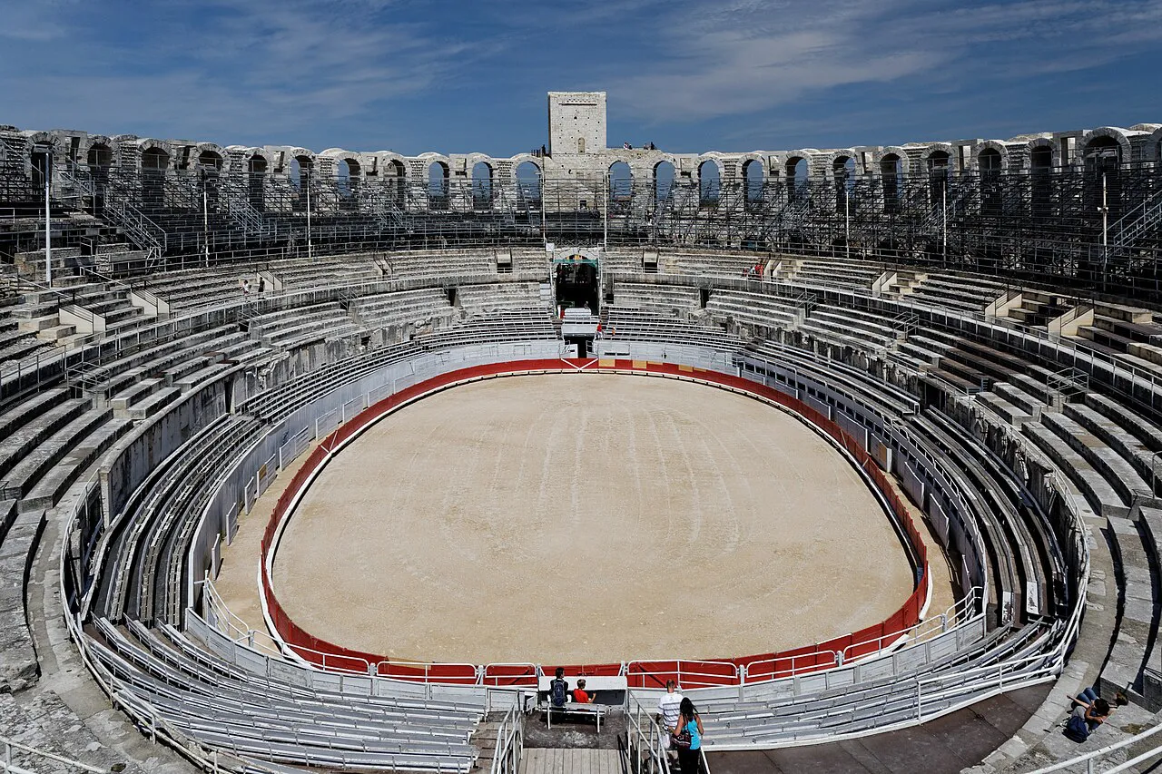 Inside the Roman amphitheatre of Arles, looking over the oval arena and stone tiers under a blue sky