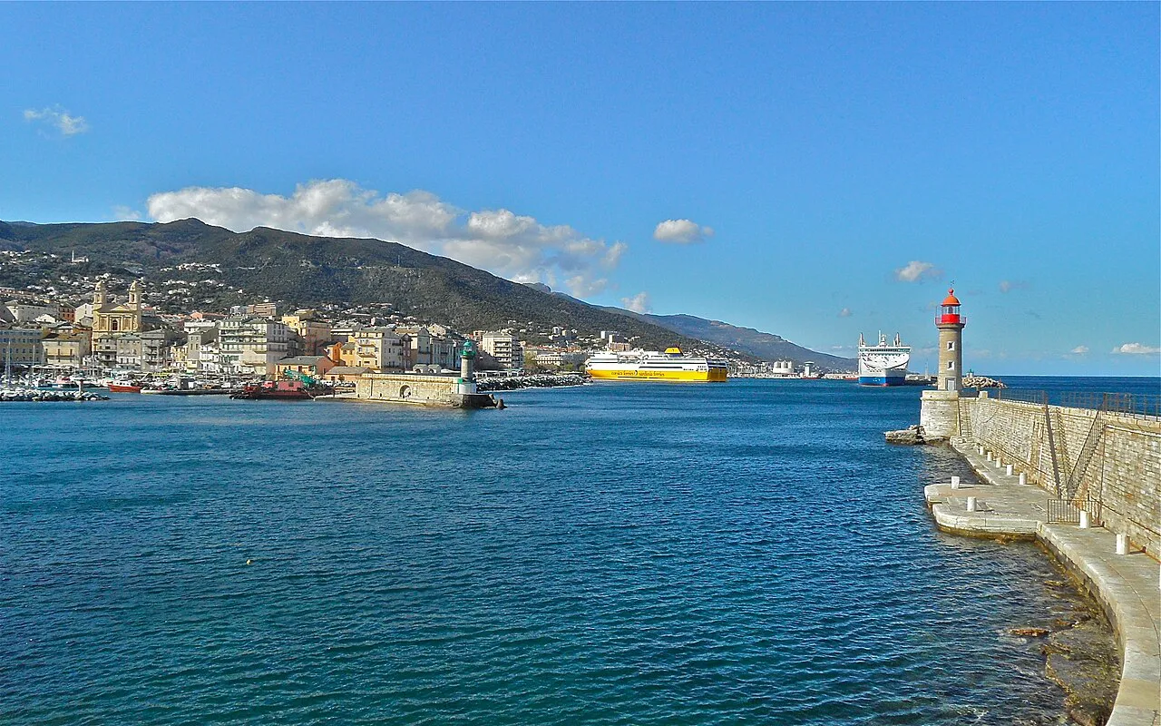 Entrance to Bastia harbour with the jetty lighthouse and the town against green hills