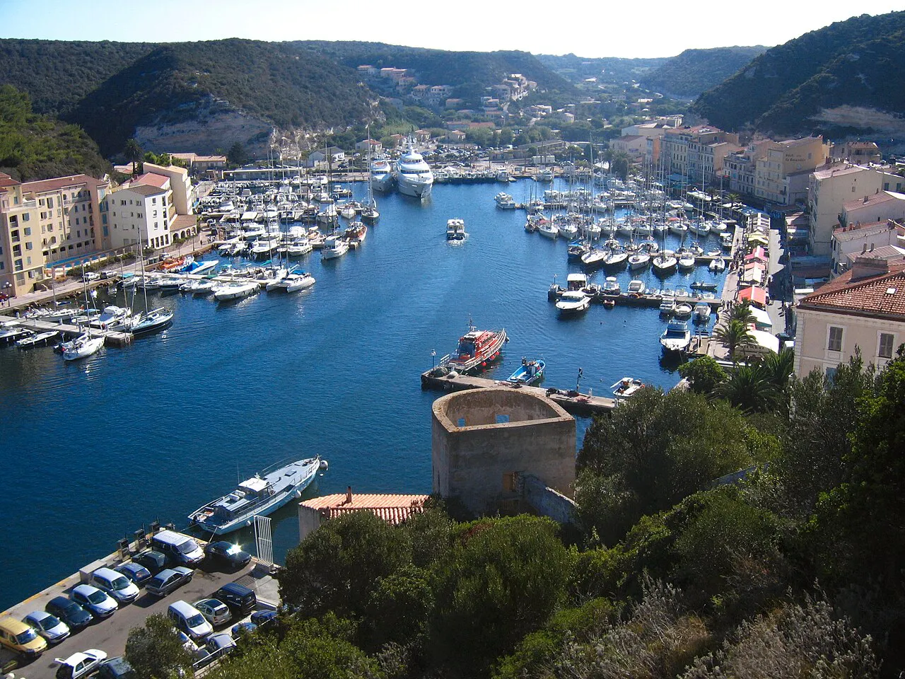 Elevated view down the long narrow harbour of Bonifacio, packed with boats between green hills