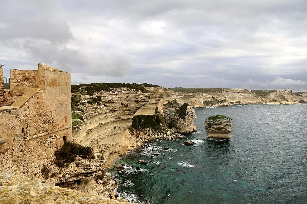 Old stone fortifications above white limestone cliffs and the Grain de Sable rock at Bonifacio