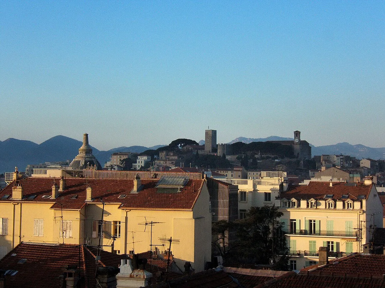 Ochre rooftops below the Suquet tower and church on the old-town hill of Cannes, with the Esterel behind