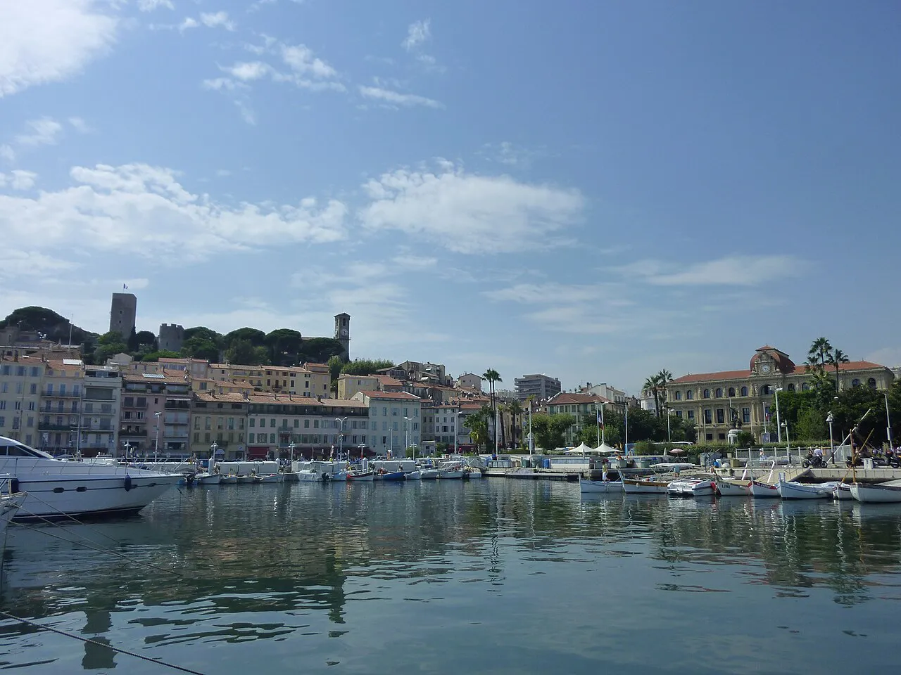Yachts moored in the Vieux Port of Cannes with the Suquet hill and its tower above the quay