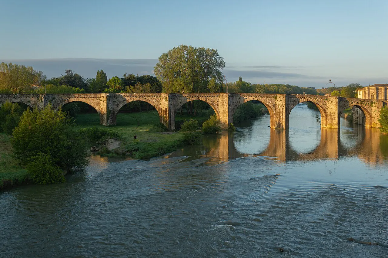 Stone arches of the Pont Vieux reflected in the Aude river at Carcassonne in evening light