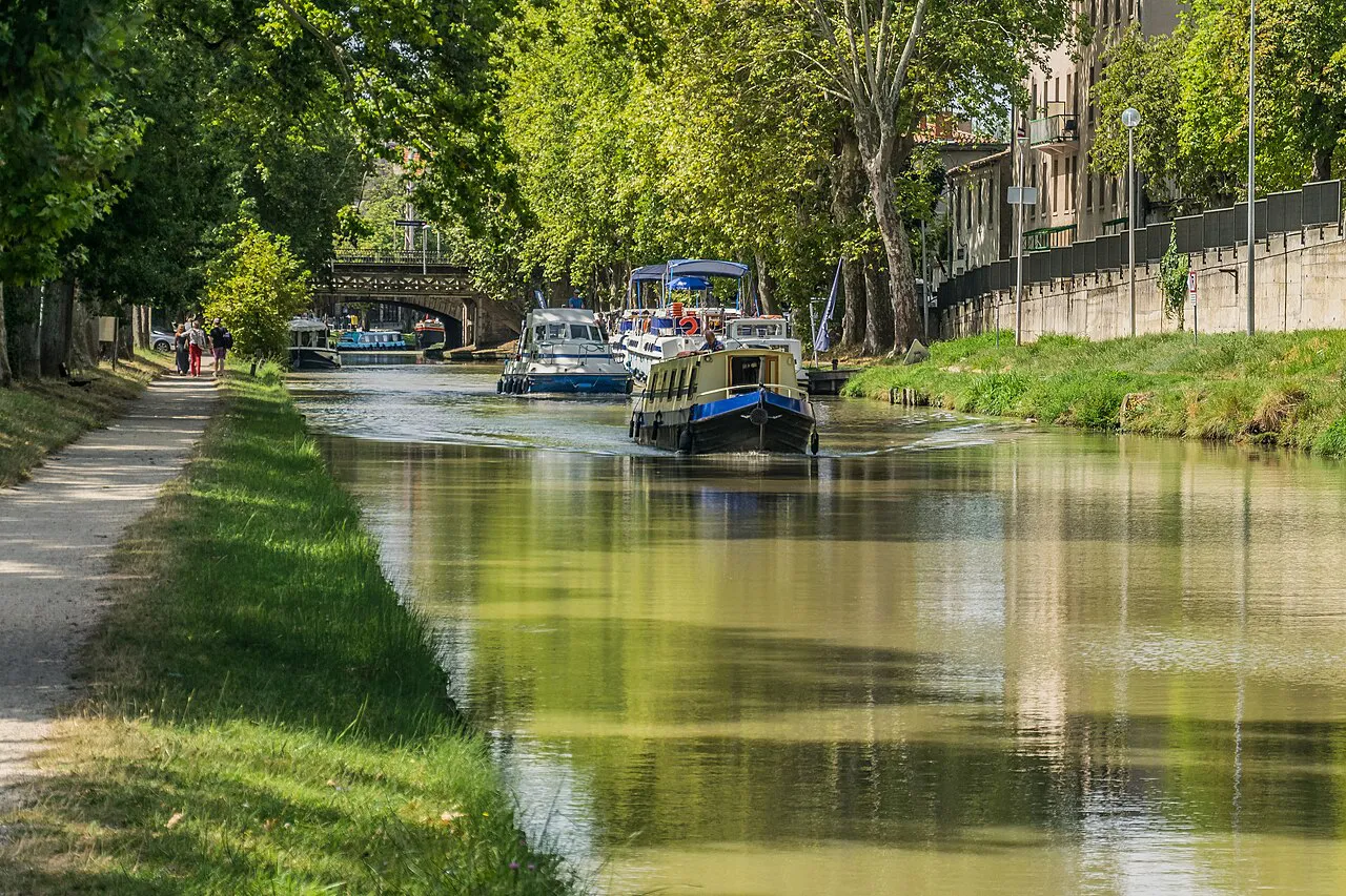 Tree-lined towpath and a moored canal boat on the Canal du Midi in Carcassonne