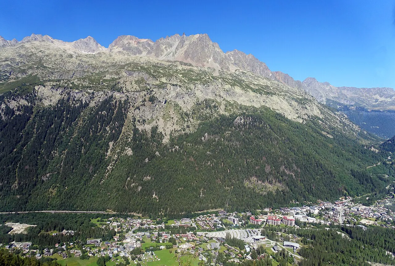Argentière village in the valley floor below forested slopes and the jagged Aiguilles Rouges