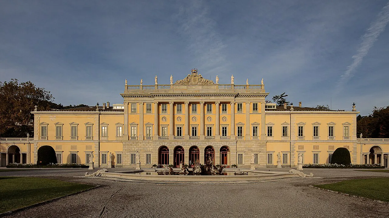 The neoclassical facade of Villa Olmo and its forecourt fountain on the lakeshore at dusk, Como