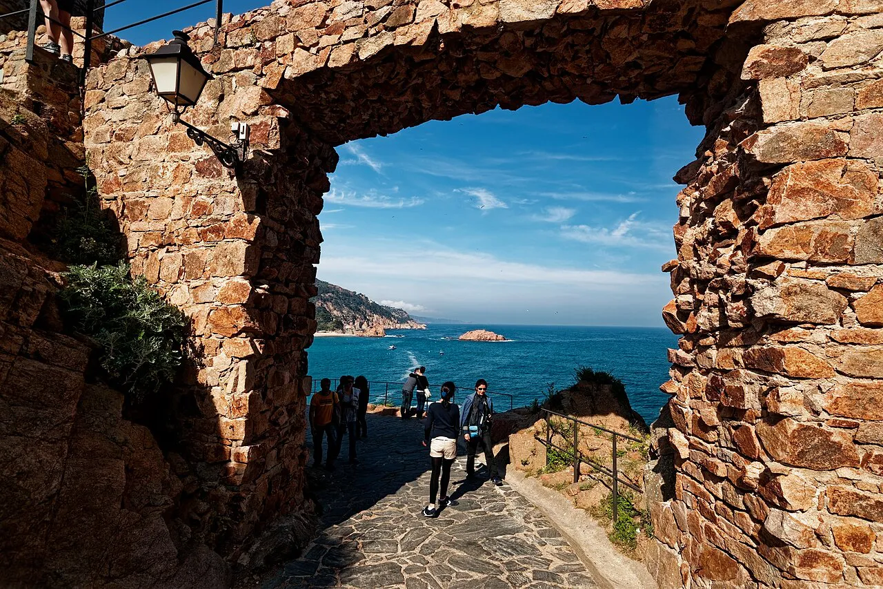 Stone archway in the medieval walls of Tossa de Mar's Vila Vella, framing the blue sea