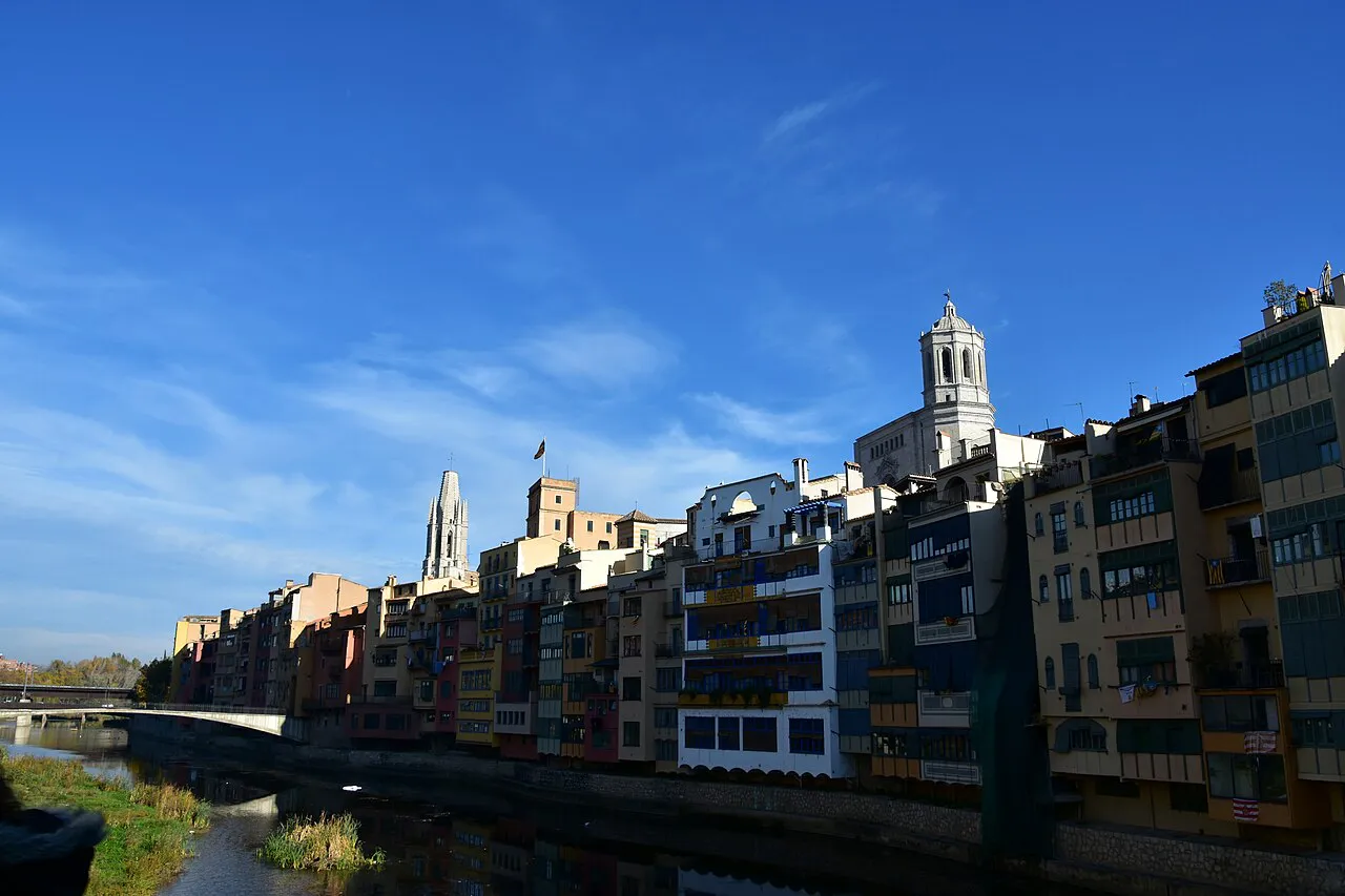 Colourful houses lining the Onyar river in Girona, with the cathedral and Sant Feliu towers above