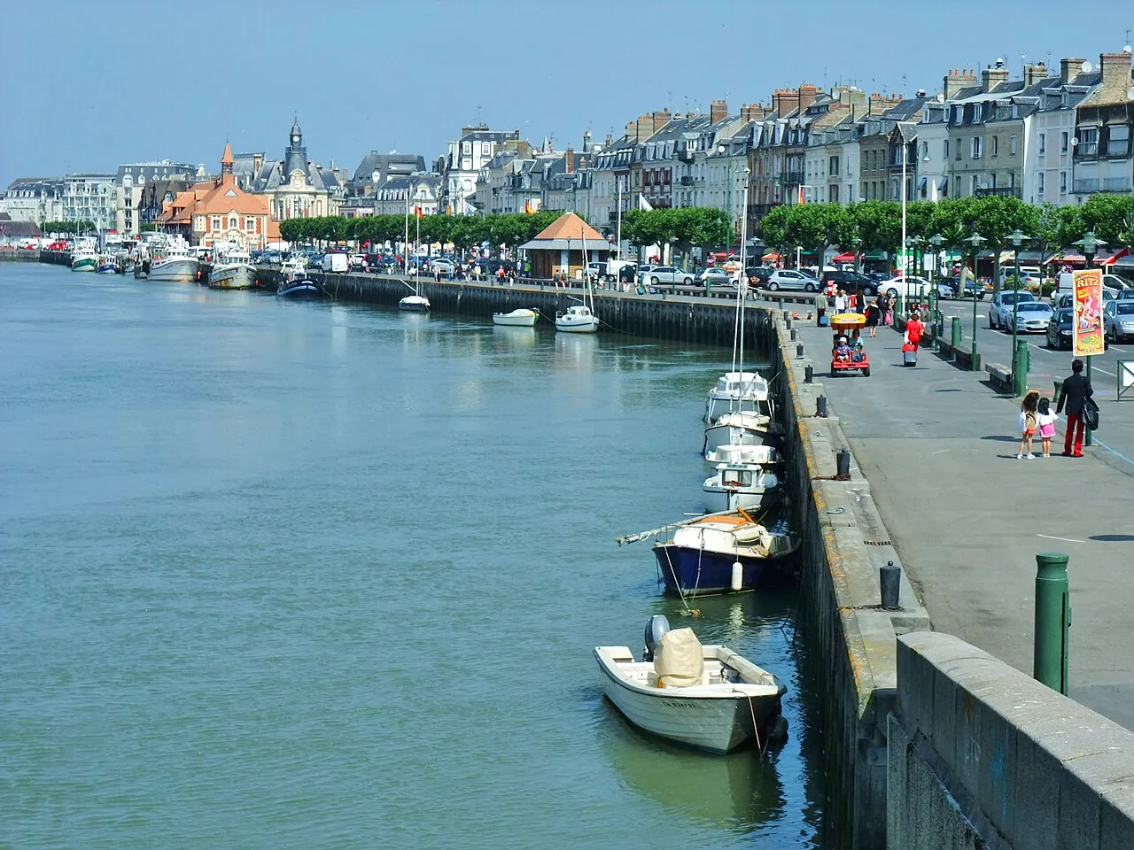Small boats moored along the Touques quay at Trouville-sur-Mer with the seafront town behind