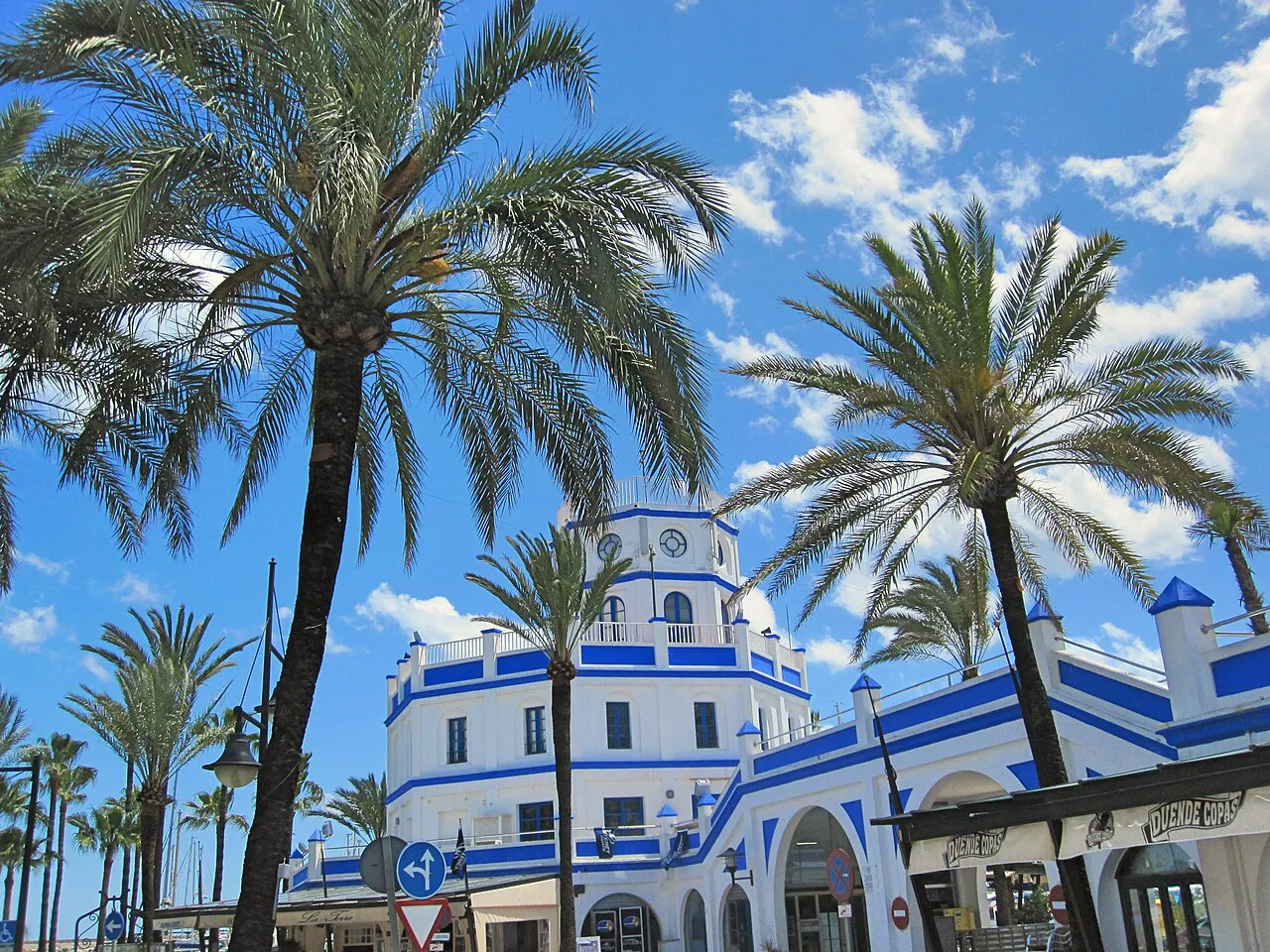 Blue-and-white marina control tower framed by palm trees at the Puerto Deportivo of Estepona