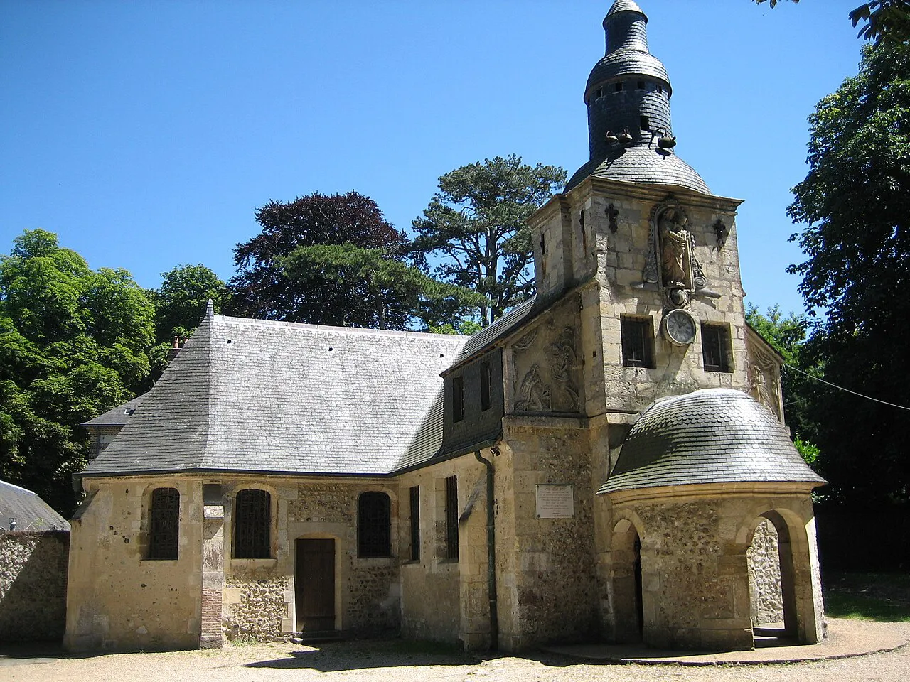Small stone Chapelle Notre-Dame-de-Grâce with its slate bell tower among trees on the heights above Honfleur