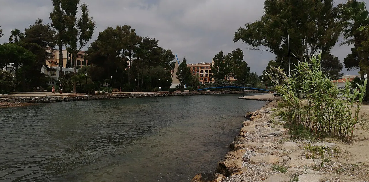The river mouth of Es Riu at Santa Eulària des Riu, lined with trees and a stone embankment