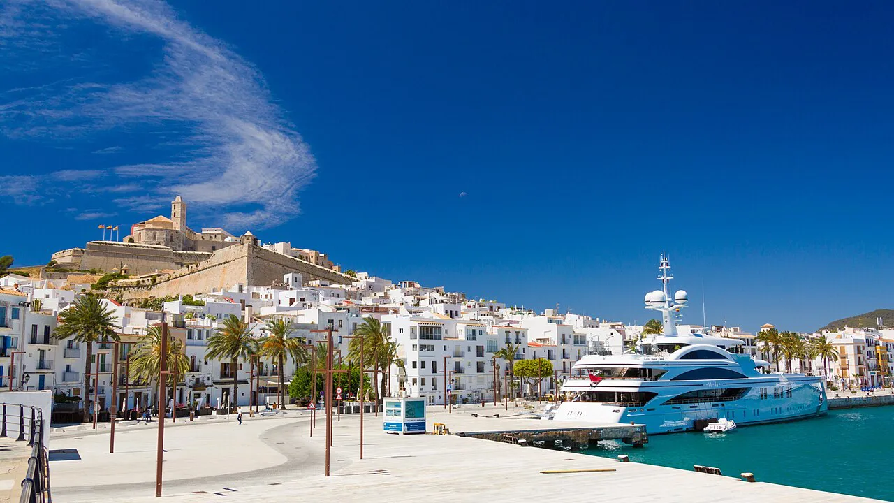 Palm-lined harbourfront of Ibiza Town with white houses climbing to the Dalt Vila walls and cathedral