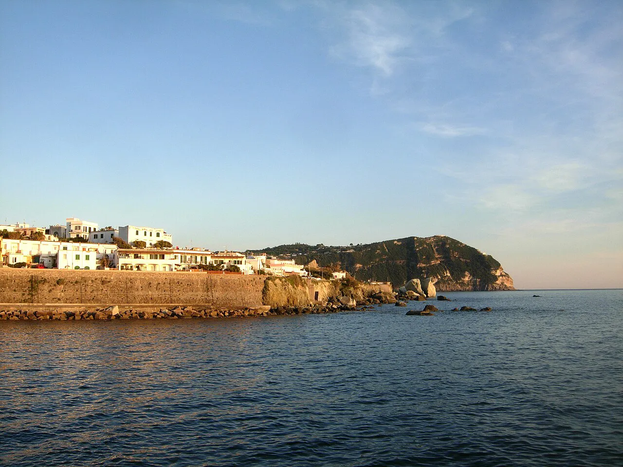 Forio's seafront wall and white houses along the coast of Ischia in soft evening light