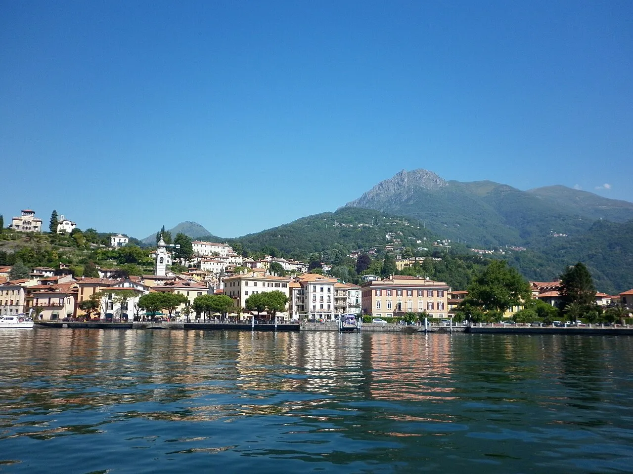 Menaggio's lakefront and church seen from the water, with mountains rising behind