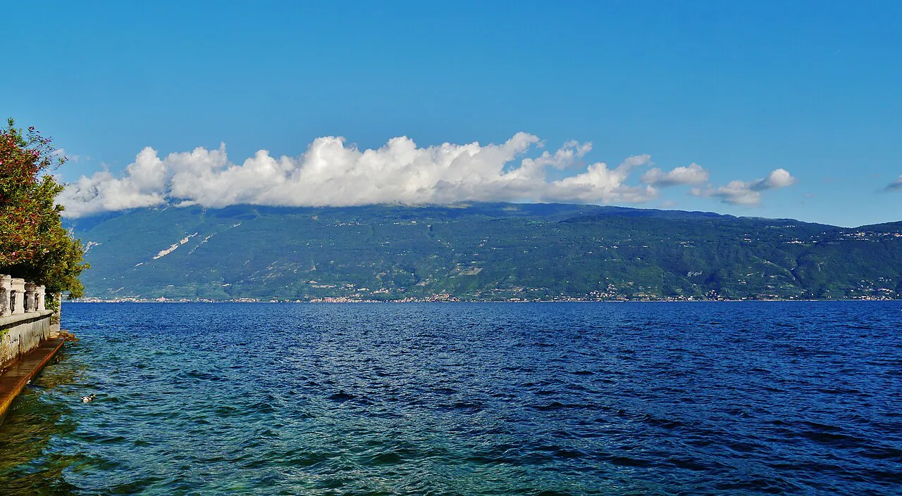 Deep blue water of Lake Garda seen from the Gargnano shore, with the far shoreline under clouds