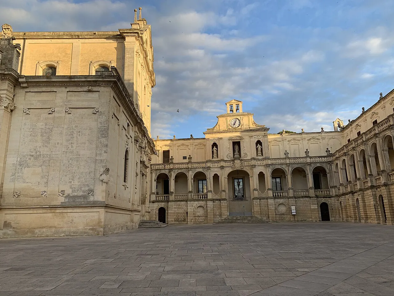 Golden limestone cathedral flank and arcaded Bishop's Palace around Piazza del Duomo in Lecce