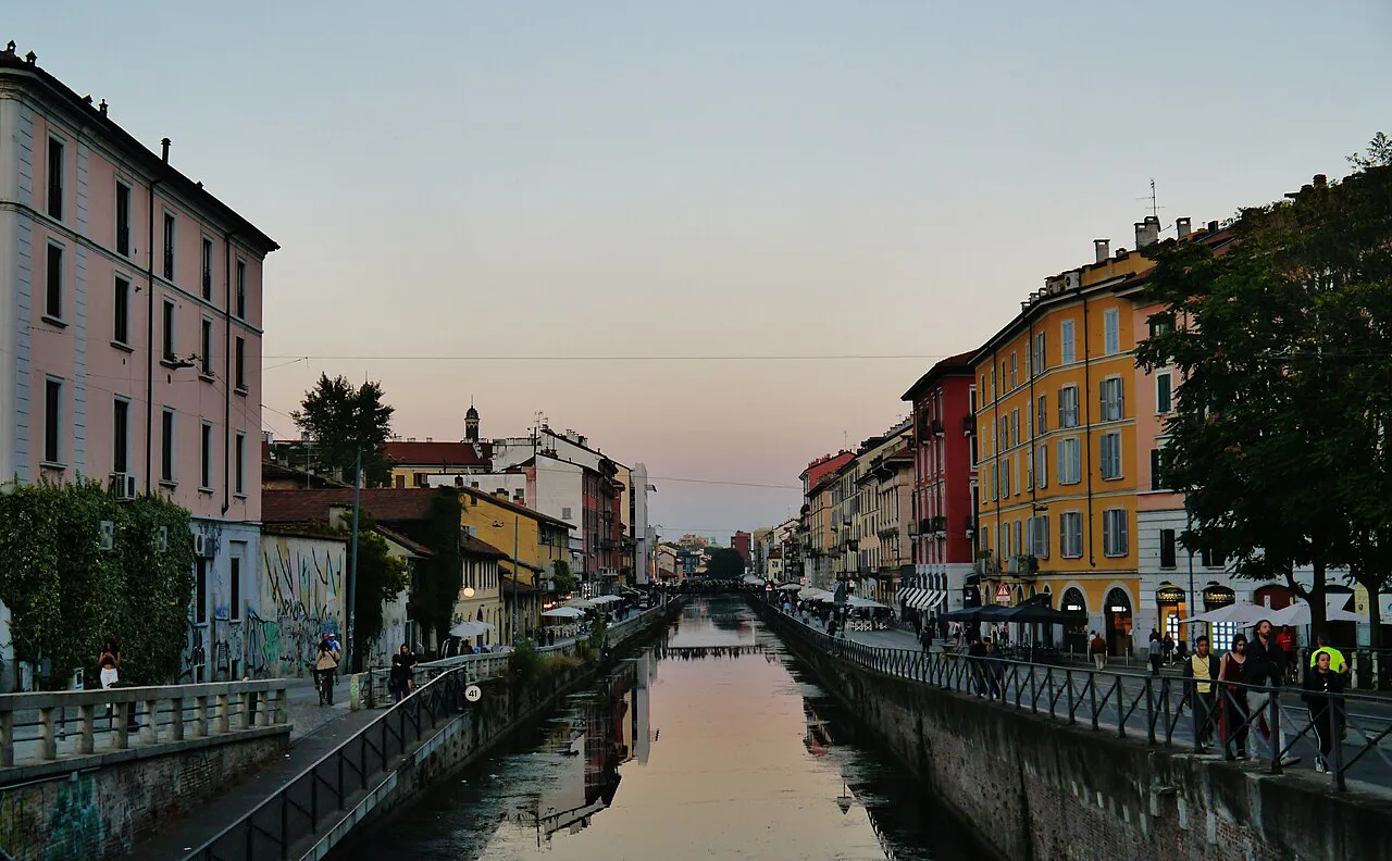 Naviglio Grande canal in Milan at dusk, lined with colourful houses and waterside paths