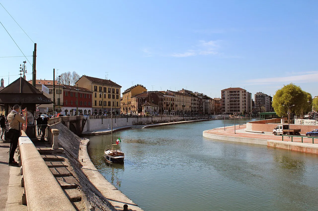 Milan’s Darsena basin on a sunny day, with a small boat and colourful buildings along the waterfront