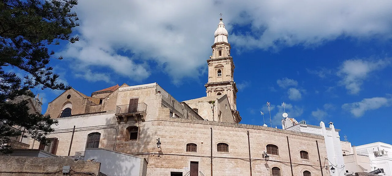 Bell tower of Monopoli Cathedral rising above pale stone buildings of the old town