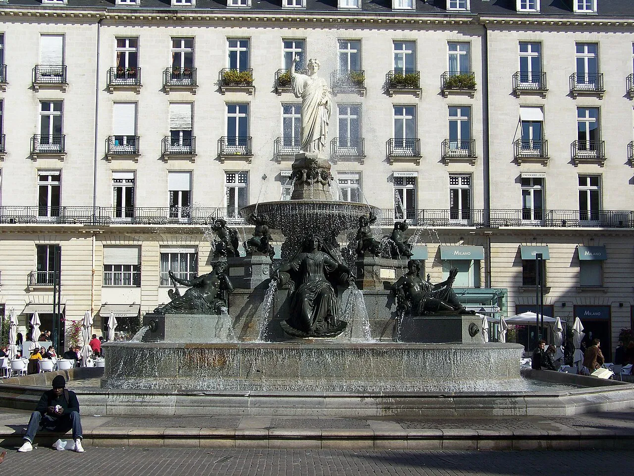 Bronze fountain on Place Royale in central Nantes in front of a uniform stone façade