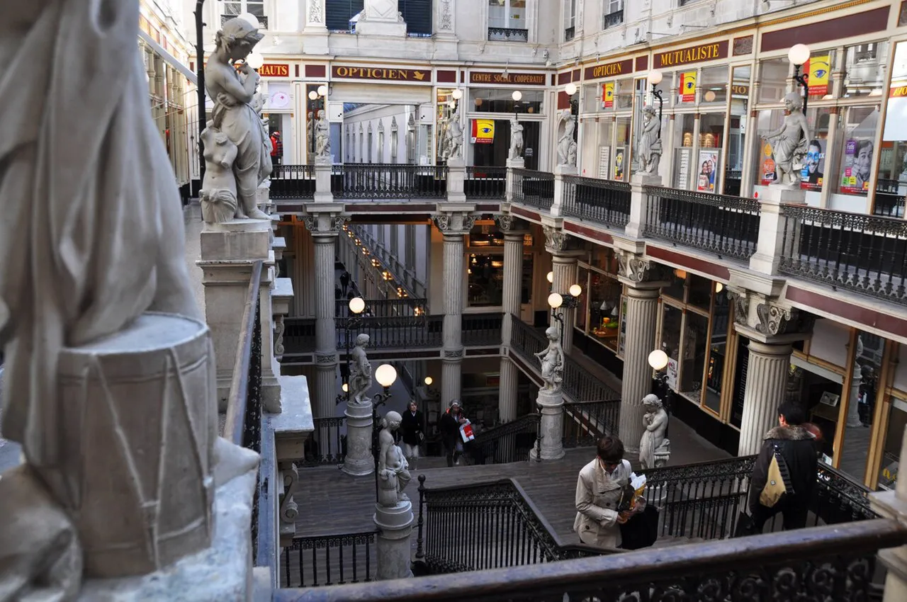 Multi-level galleries, staircases and statues inside the 19th-century Passage Pommeraye in Nantes