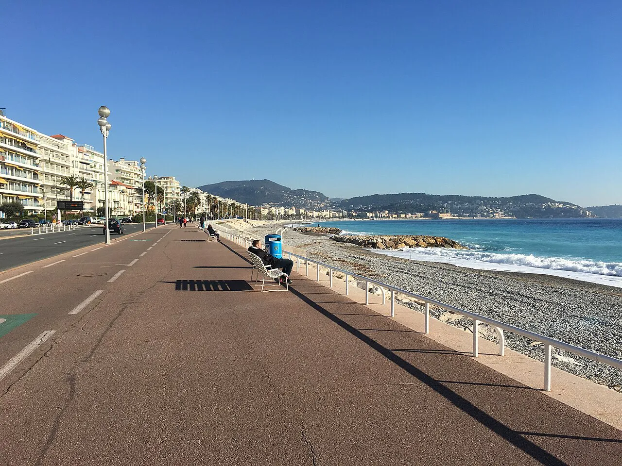 Wide seafront walkway of the Promenade des Anglais beside the pebble beach in Nice on a sunny day