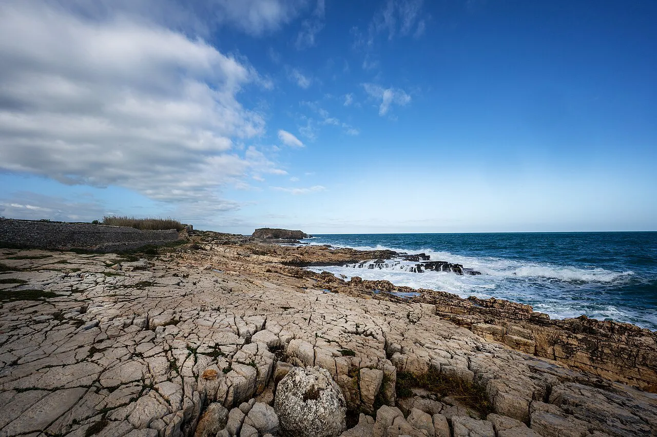 Flat limestone rocks and low cliffs on the Polignano a Mare coast under a wide blue sky