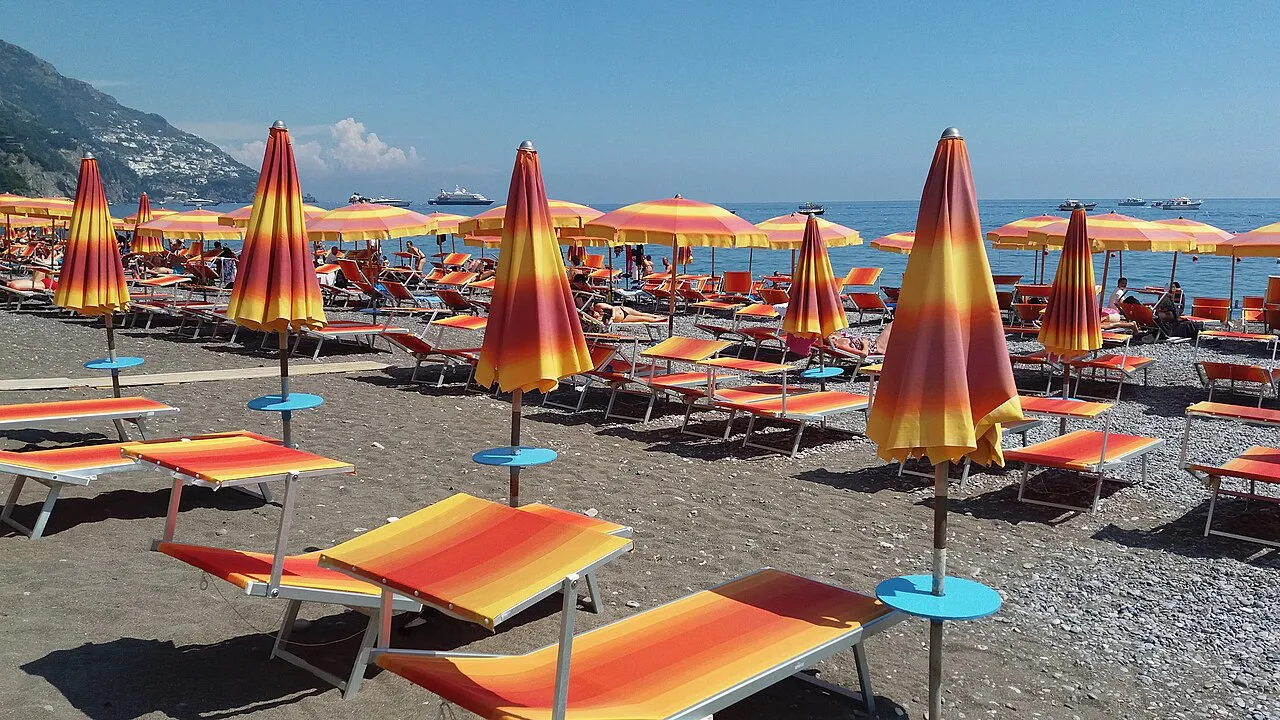 Rows of orange and yellow striped parasols and loungers on the Spiaggia Grande beach in Positano