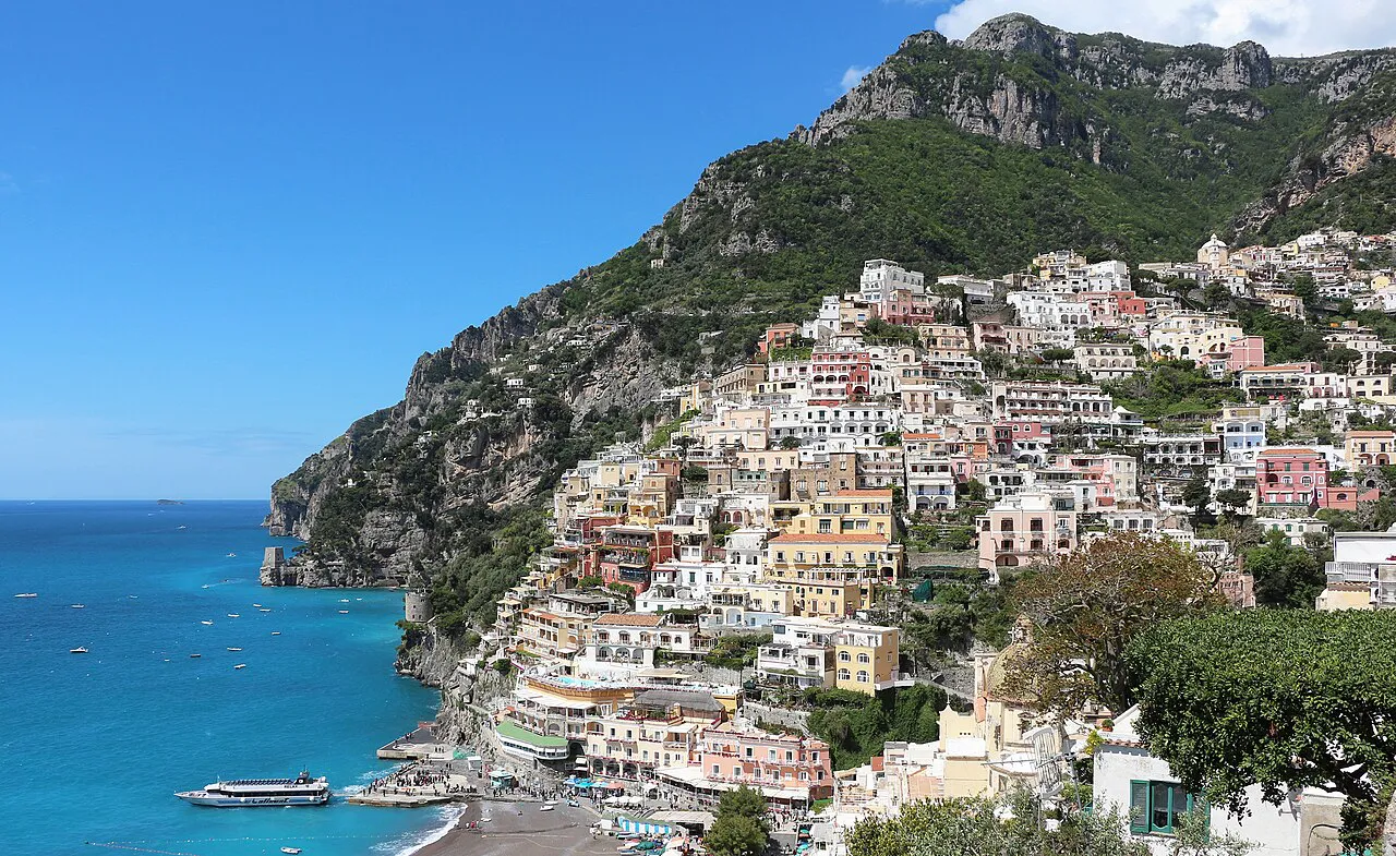 Pastel houses of Positano stacked down the cliff to the sea below the mountains of the Amalfi Coast