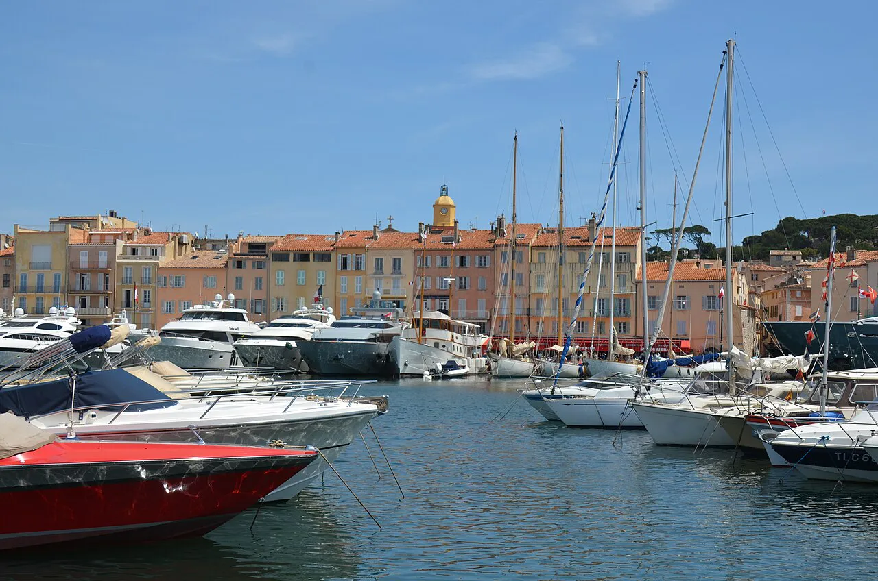 Boats in Saint-Tropez harbour in front of pastel quayside houses and the church bell tower