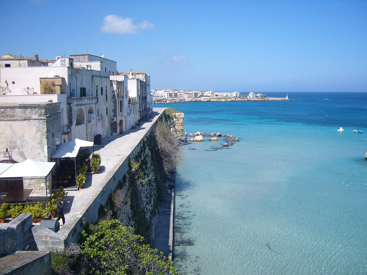 Seafront walls and white buildings of Otranto beside clear turquoise Adriatic water